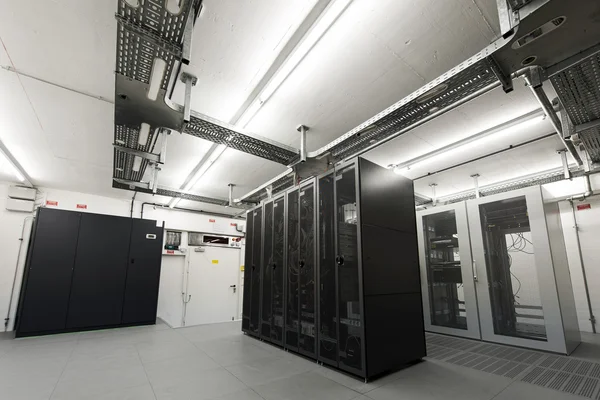 Small air conditioned cooled data server room with black racks and cable trays on ceiling