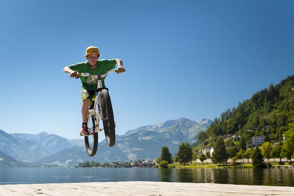 Young male teenager jumps high with his dirt bike on a lake base
