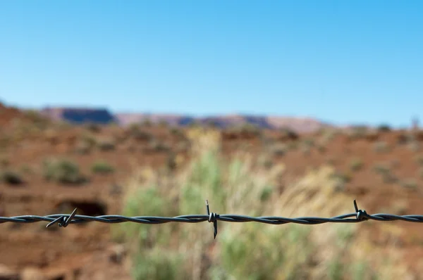 Barbed wire fence made of steel in front of desert and blue sky in the USA