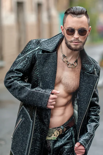 Man in  glasses on the street in a leather coat.