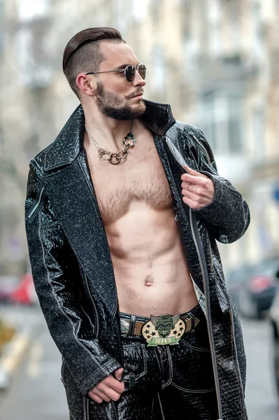 Man in  glasses on the street in a leather coat.