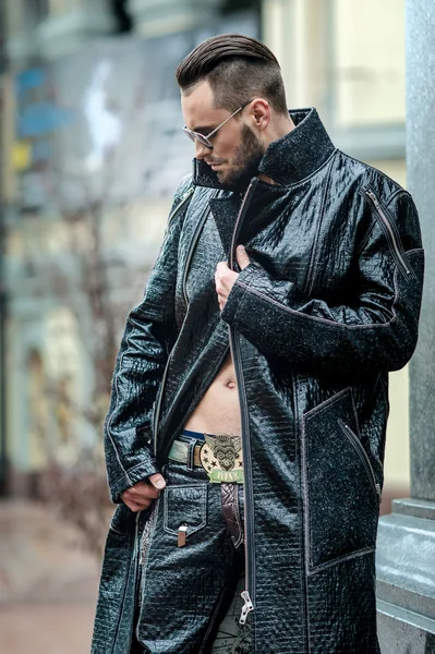 Man in  glasses on the street in a leather coat.
