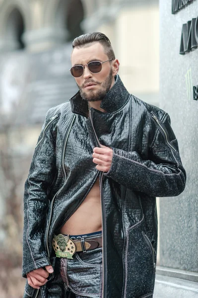 Man in  glasses on the street in a leather coat.