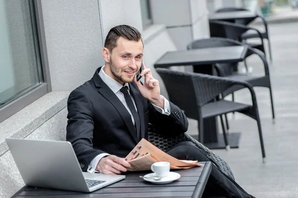 Businessman talking on the phone and reading  newspapers