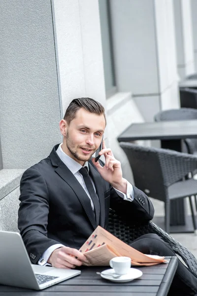 Businessman talking on the phone and reading  newspapers