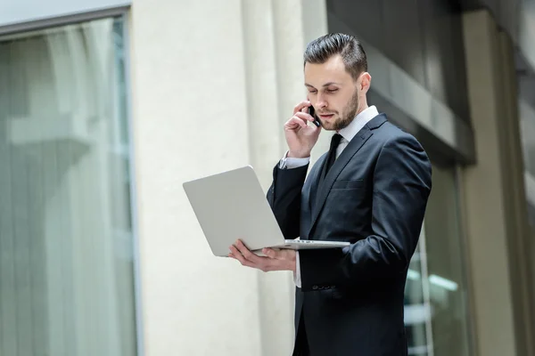 Businessman talking on the phone and  holding a laptop