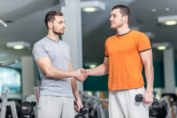 Hello athletes. Two athletes shake hands at the fitness club. Tw