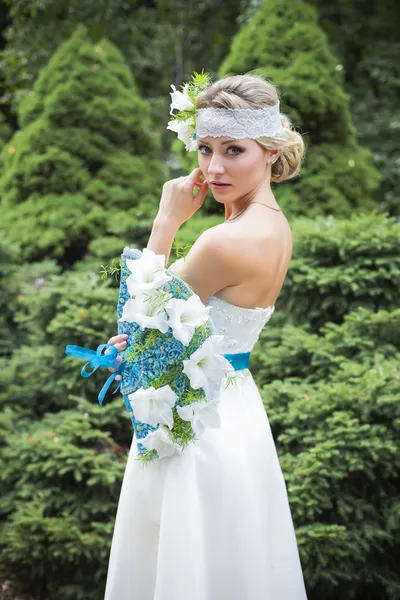 Blonde woman in wedding dress holding bouquet with white lilies