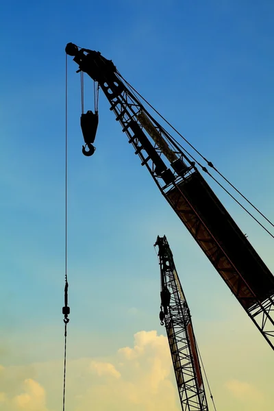 Yellow hoisting crane under blue sky