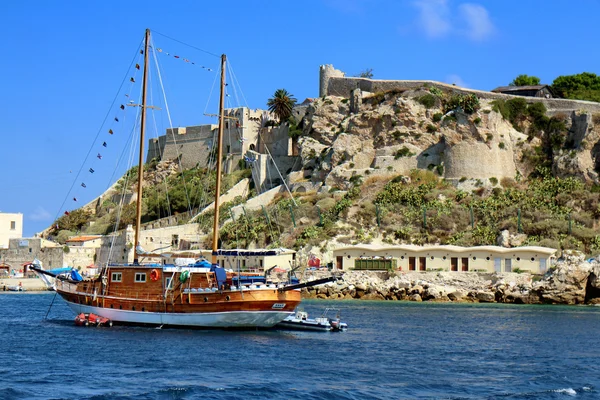 Wooden sailing ship passing by ancient island fortress