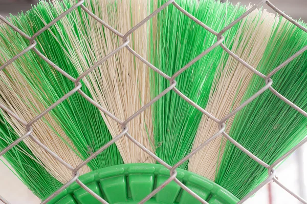 Green and white broom and wire mesh