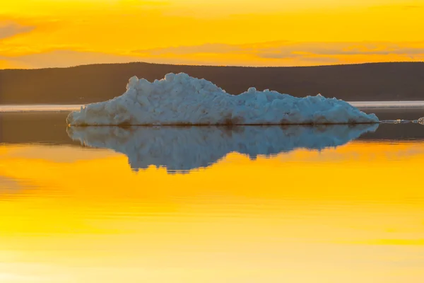 The melting iceberg on spring mountain lake in the setting sun.