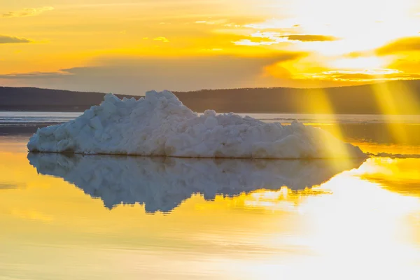 The melting iceberg on spring mountain lake in the setting sun.