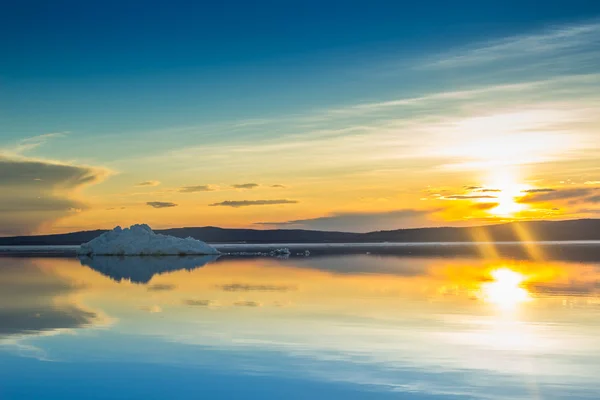 The melting iceberg on spring mountain lake in the setting sun.