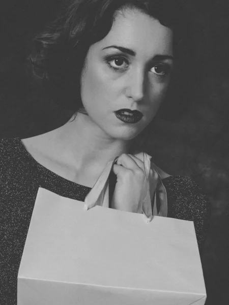 Vintage monochrome picture of young woman holding shopping bag