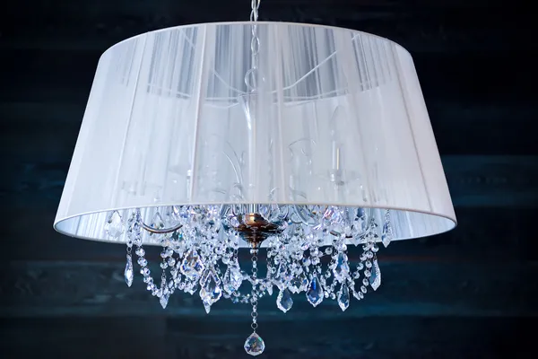 A crystal chandelier with a white shade
