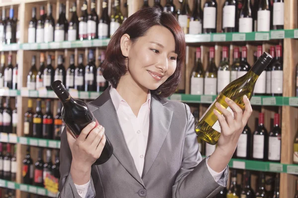 Mid Adult Woman Choosing Wine in a Liquor Store