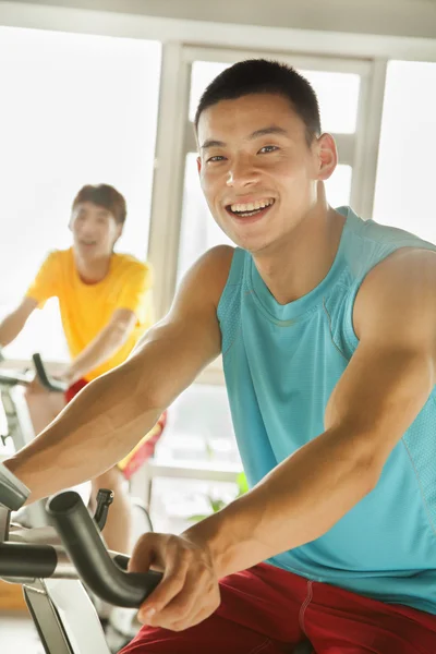 Young men on stationary bikes exercising in the gym