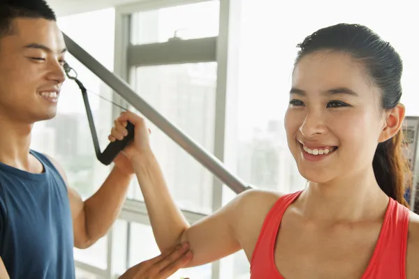 Young woman exercising with his personal trainer in the gym