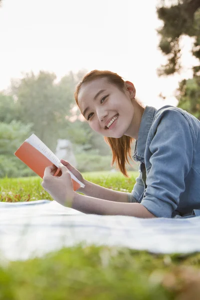Teenage girl reading book in the park