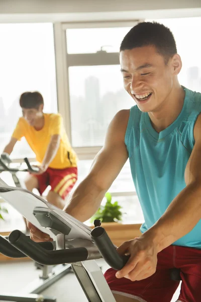 Young men on stationary bikes exercising in the gym