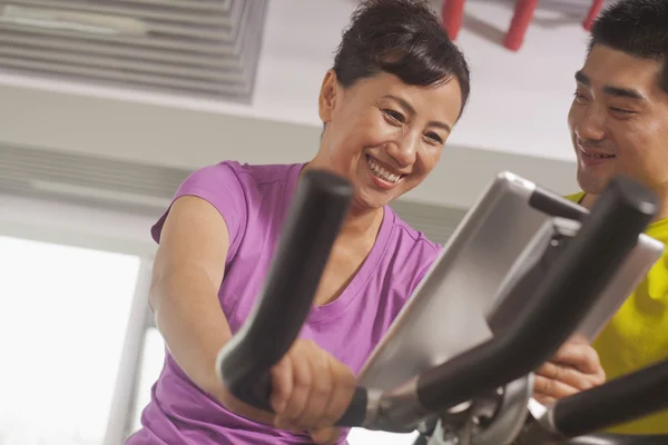 Woman exercising on the exercise bike with her trainer