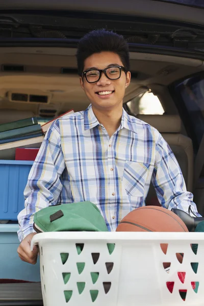 Boy with college dorm items in back of car