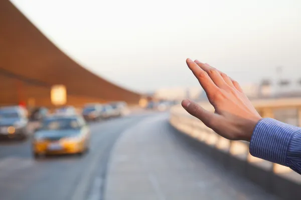 Hand of traveler hailing a taxi
