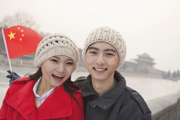 Couple holding Chinese flag outdoors in wintertime