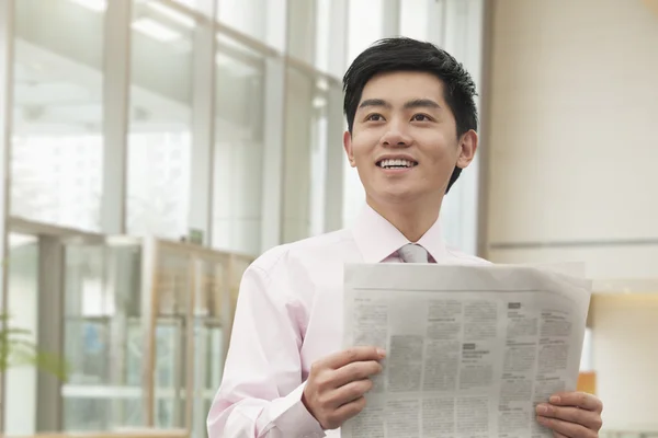 Businessman in pink button down shirt reading newspaper