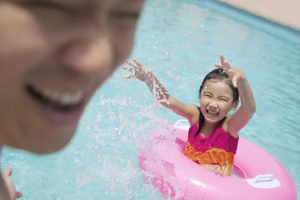 Girl and her father splashing in the pool