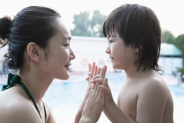 Mother and son holding hands by the pool
