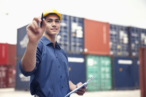 Engineer in a shipping yard examining cargo