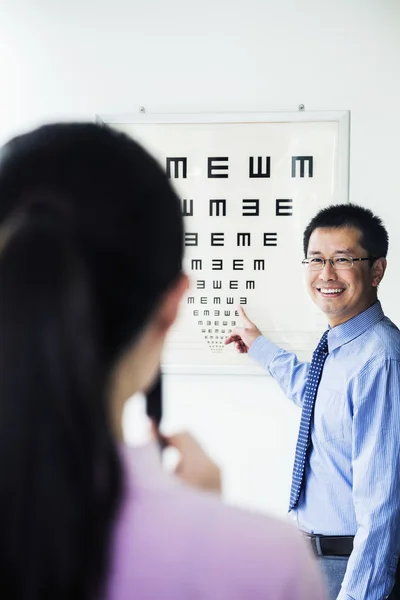 Optometrist administering an eye exam on a eye chart