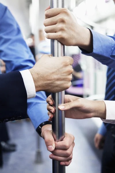 Business people\'s hands holding the pole on the subway