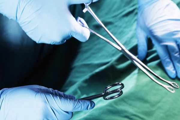 Gloved hands holding the surgical scissors