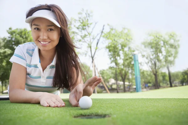 Smiling young woman lying down in a golf course