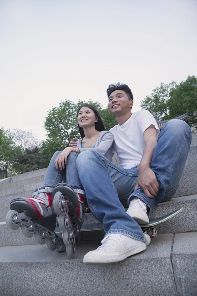 Couple with a skateboard and roller blades