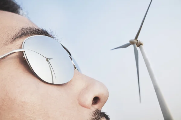 Mans face with the reflection of the wind turbine