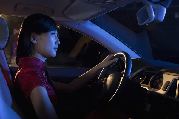 Woman in a traditional Chinese dress driving at night