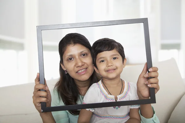 Mother and daughter holding up a picture frame