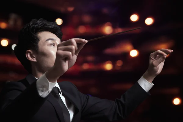 Conductor with baton raised at a performance
