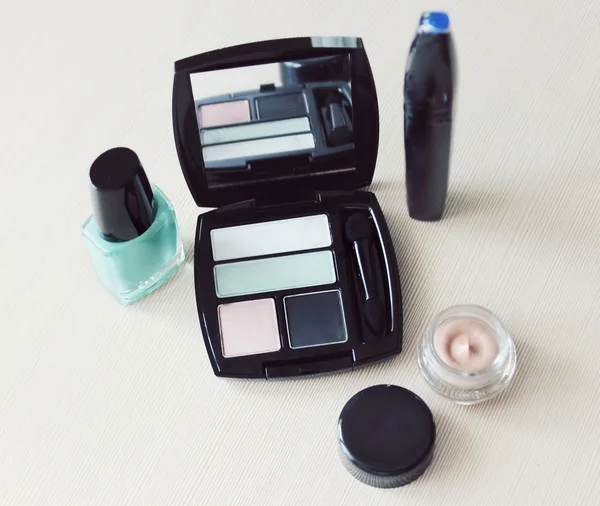 Set of eyeshadow, mascara, primer, turquoise blue nail polish on a dressing table