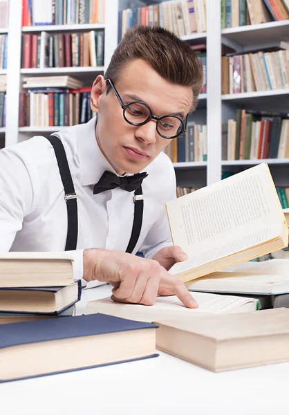 Young nerd man in shirt and bow tie reading book