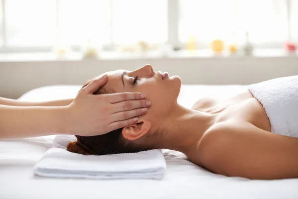 Woman lying on back while massage therapist touching her face