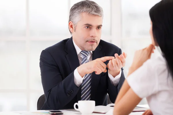 Confident senior man in formalwear talking to young woman