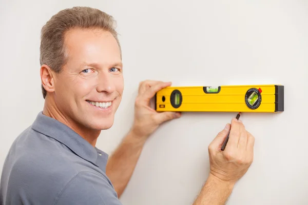 Cheerful mature man taking measurements of the wall