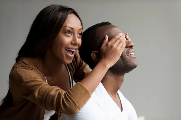 African woman covering her boyfriend eyes