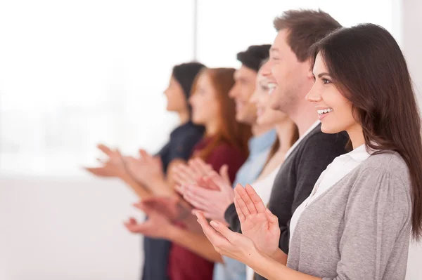 Side view of group of people standing in a row and applauding