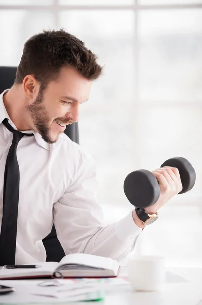 Beard man in shirt and tie training with dumbbell and smiling